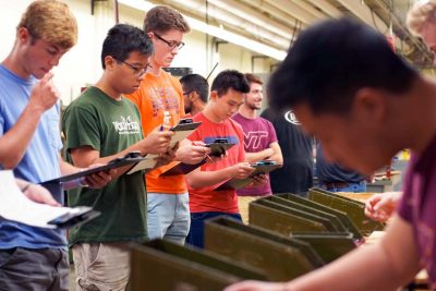 ISE students with clipboards studyinga process in a lab.