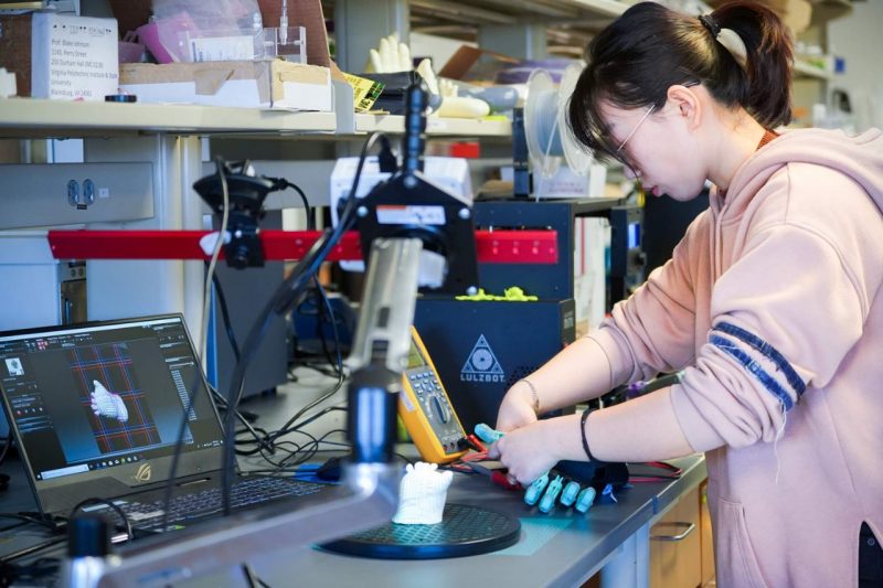A woman holds a blue prosthetic and adjusts it in a lab.
