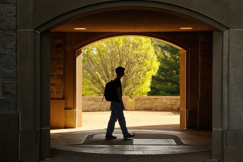 student walks through an archway on campus